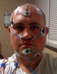 A picture of Scott with all sorts of wires and stickers stuck on his head