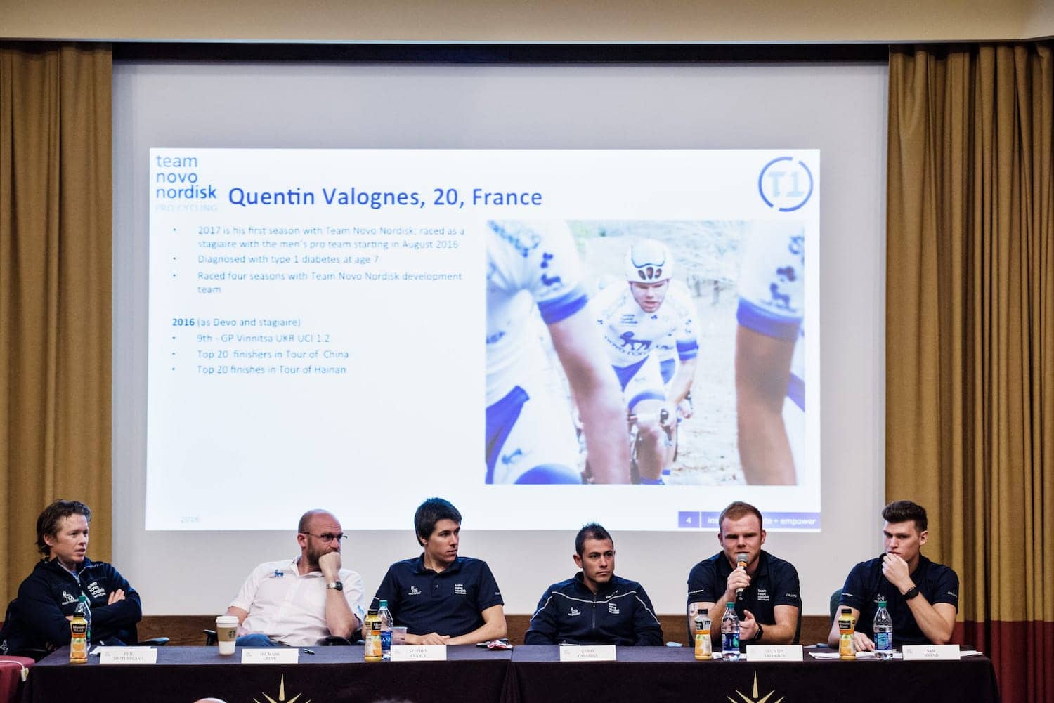 Panel of Team Novo Nordisk cyclists with Quentin speaking into a microphone